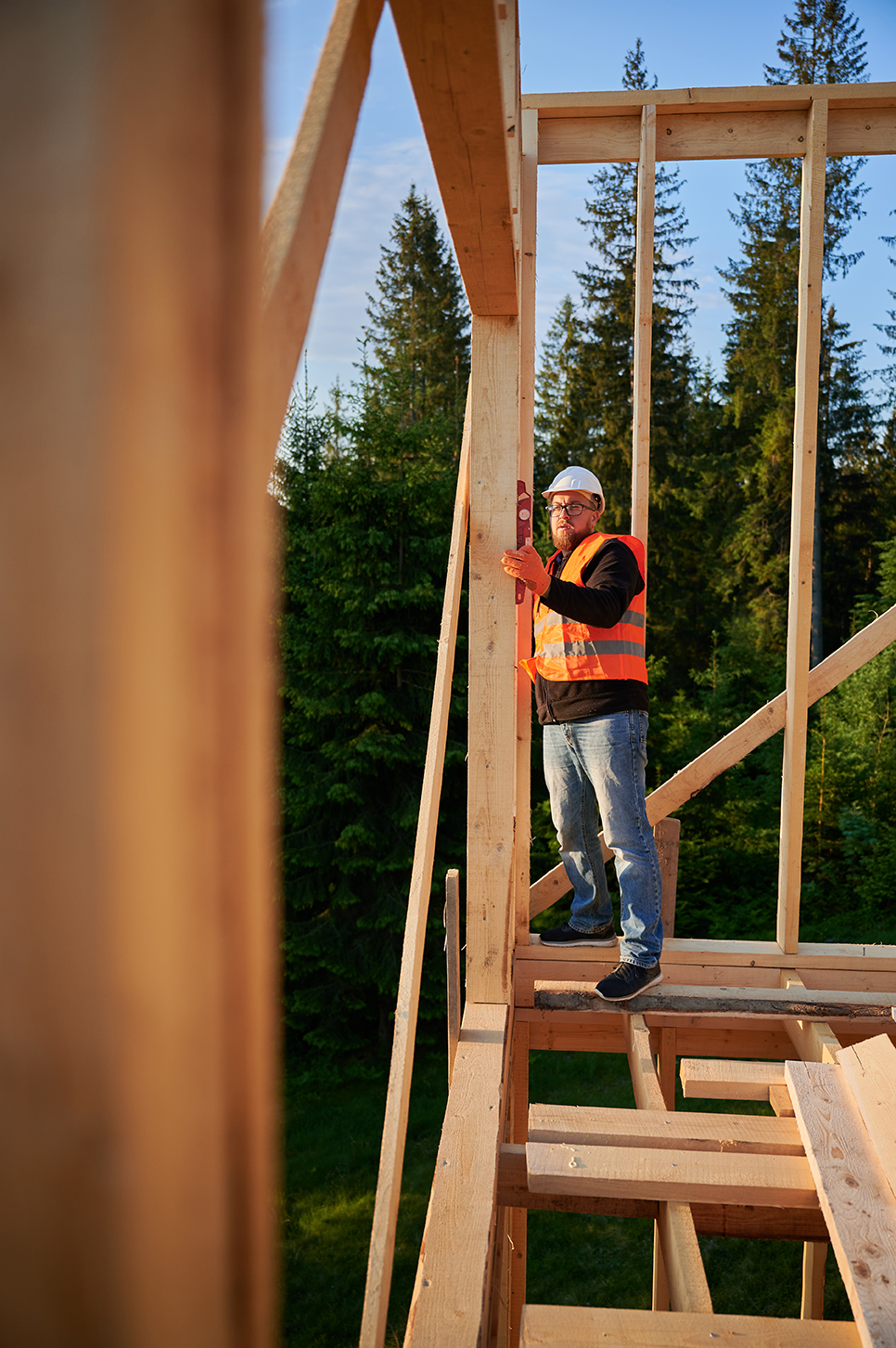 Ouvrier contrôlant l'ossature bois d'une maison individuelle avec un niveau